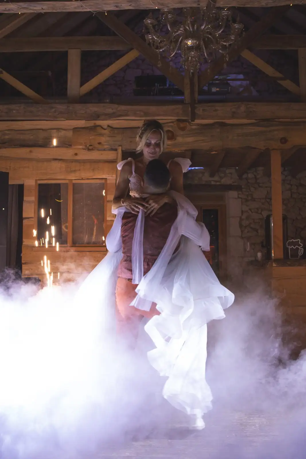 Le marié soulève sa femme à bout de bras, la robe flottant dans la fumée