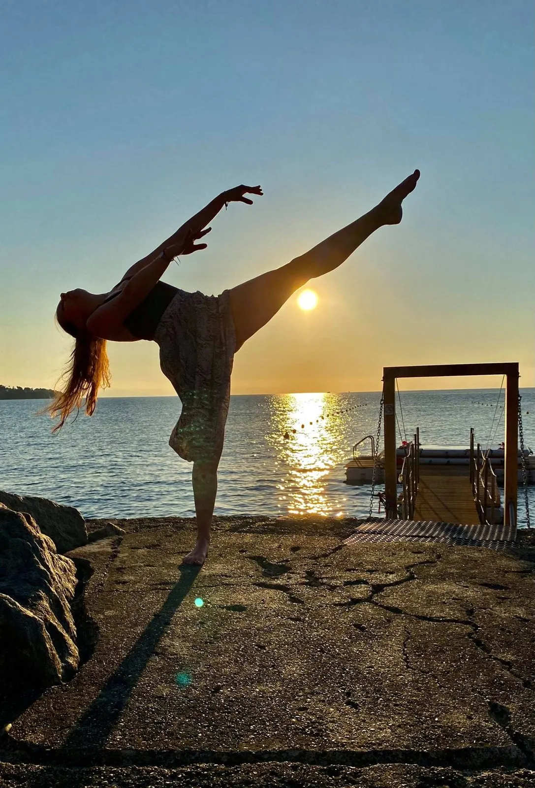 Pauline en silhouette au coucher du soleil, jambe tendue à l’horizontale