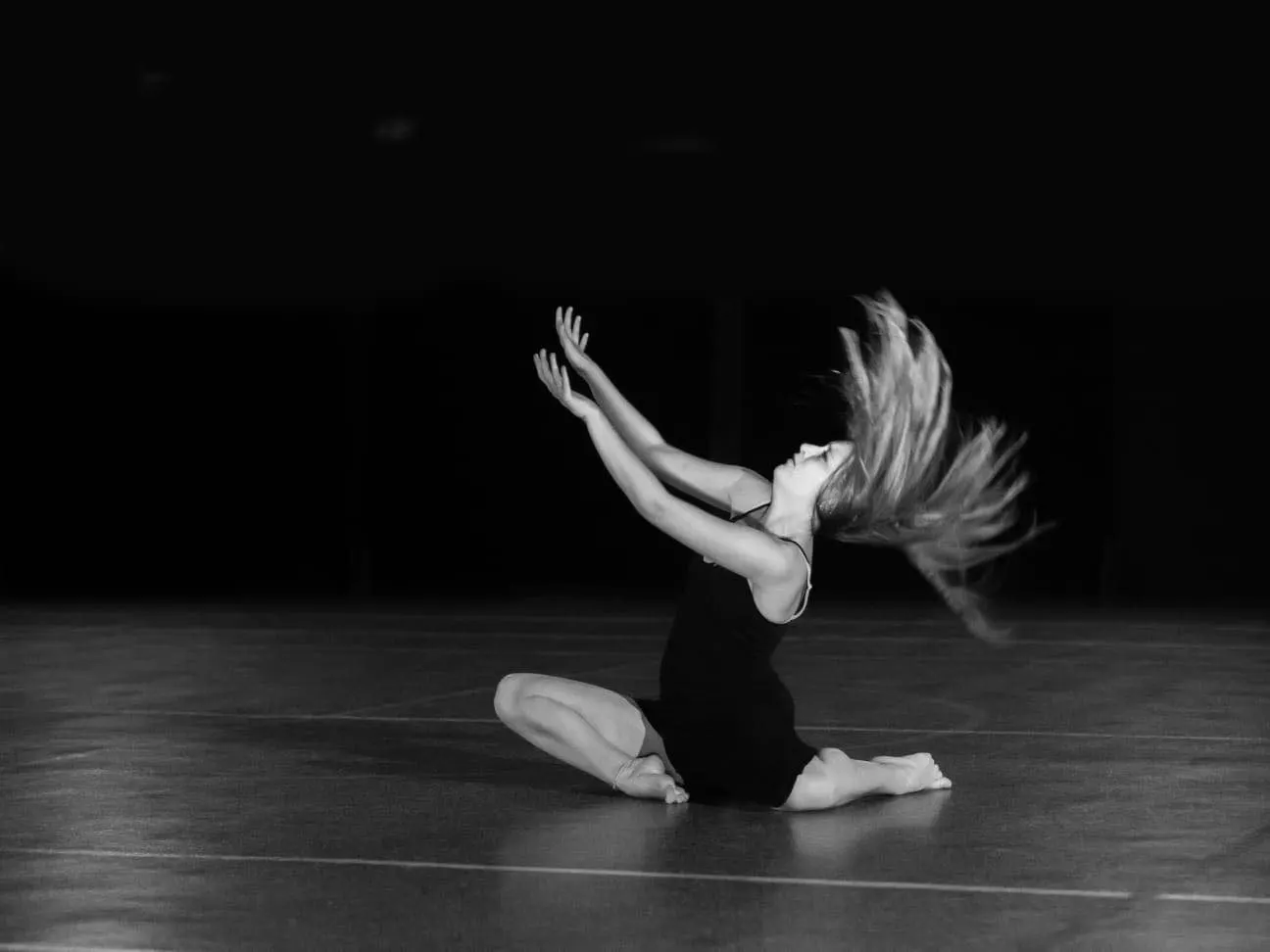 Pauline au sol, en noir et blanc, cheveux en mouvement, bras levés
